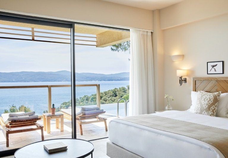 Luxurious premium suite with private infinity pool overlooking azure Aegean Sea, featuring modern minimalist design and panoramic views of scenic Greek island landscape