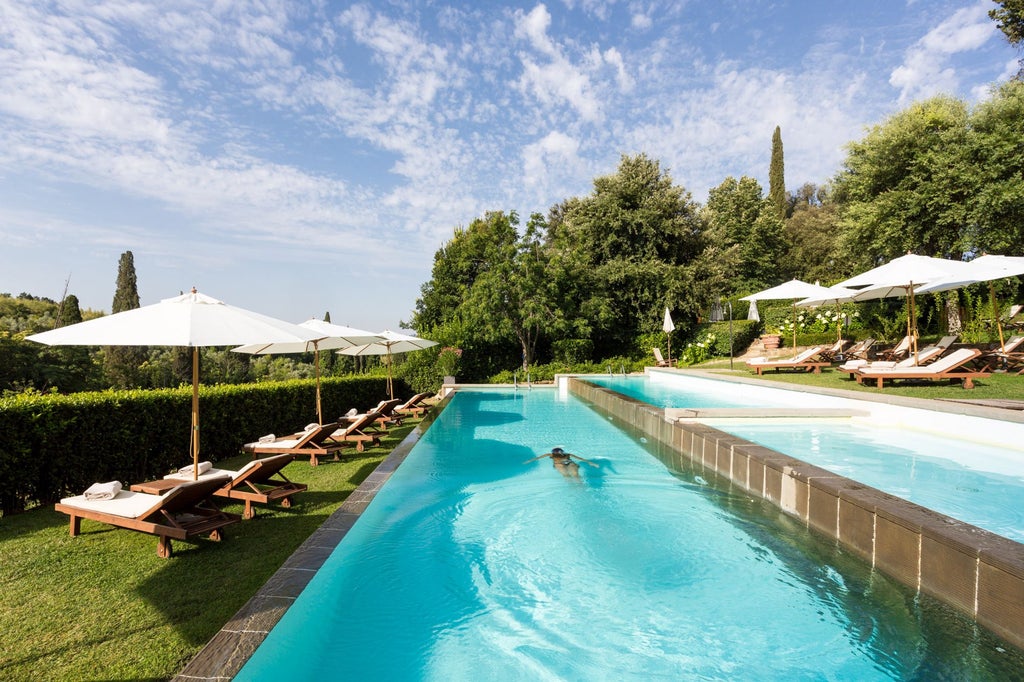 Elegant Renaissance villa hotel nestled on Tuscan hillside with manicured gardens, stone facade and panoramic Florence views