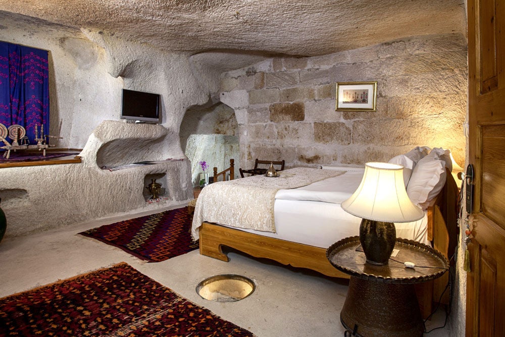 Luxurious cave hotel suite built into volcanic rock formations in Cappadocia, featuring arched doorways and traditional Turkish decor