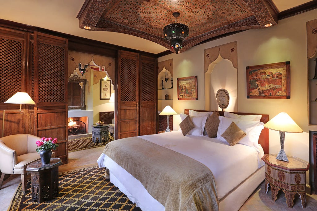 Historic Moroccan luxury hotel exterior with ornate archways, traditional lanterns, and lush courtyard garden featuring a fountain