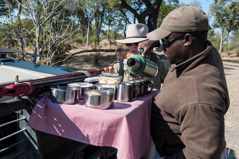 Elevated luxury tent overlooking African savanna, with private wooden deck, canvas walls and elegant safari-style furnishings at sunset