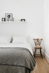 Chic Lisbon apartment with modern minimalist design, featuring light wooden floors, white walls, and a plush queen-sized bed with crisp linens