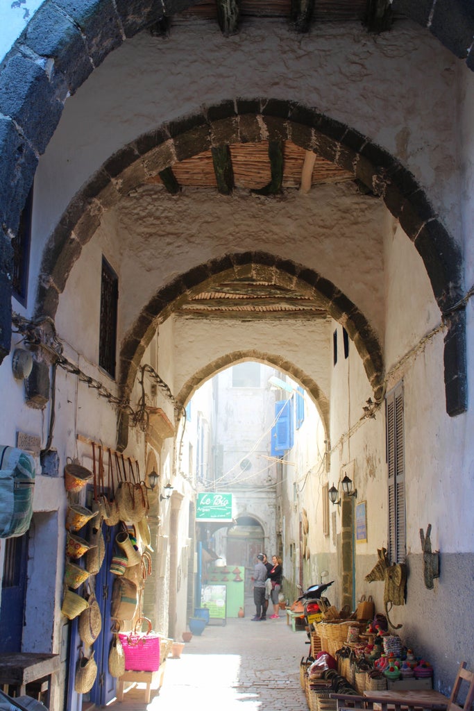 Blue-painted buildings cascade down a hillside in Chefchaouen, Morocco, with narrow alleyways and traditional architecture under clear skies