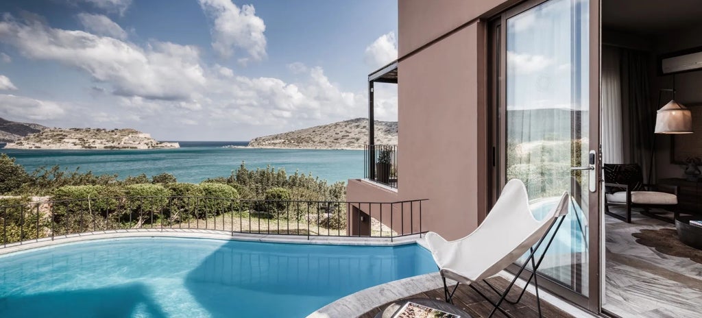 Luxurious family suite with private outdoor jacuzzi overlooking azure Aegean waters, elegant white-domed architecture and scenic Cretan landscape in Elounda, Greece