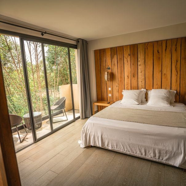 Elevated wooden lodge with floor-to-ceiling windows nestled in Madagascar's rainforest, featuring a wraparound deck and mountain views