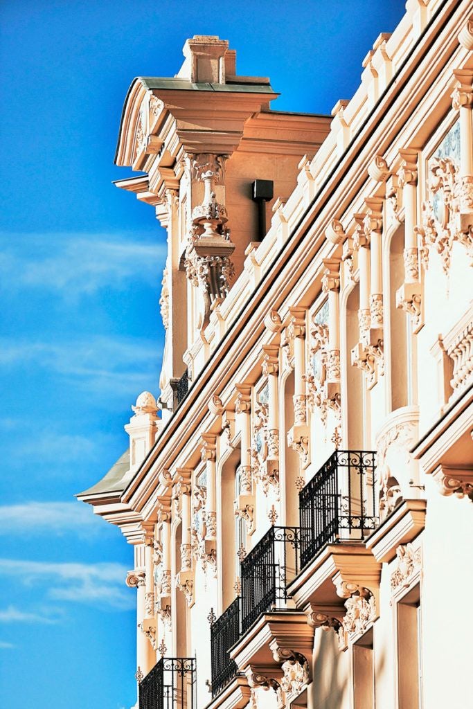 Luxurious boutique hotel with elegant white facade, ornate balconies, and classic Spanish architectural details in Madrid's upscale neighborhood