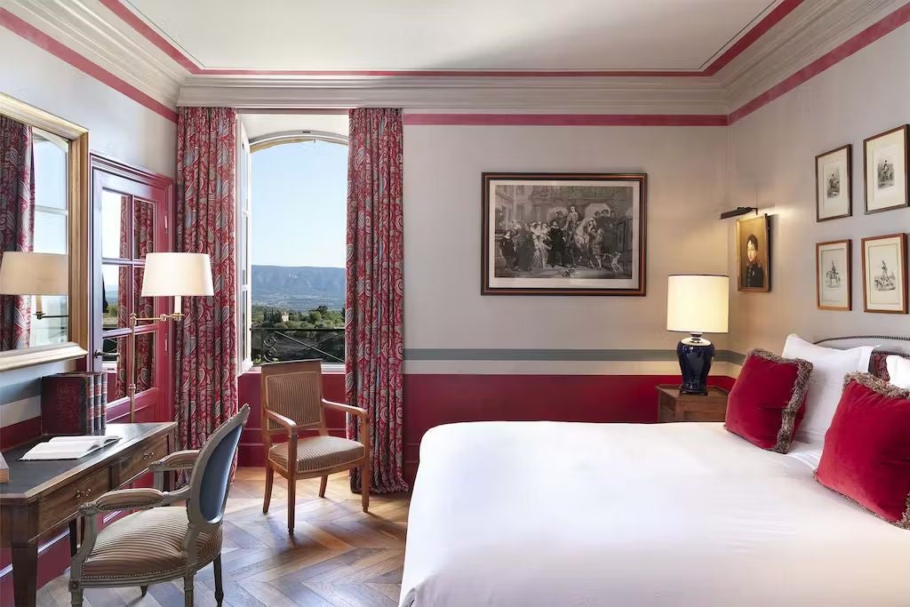 Historic luxury hotel built into limestone cliffs, with stone facade, terraced gardens and panoramic views of Provence countryside