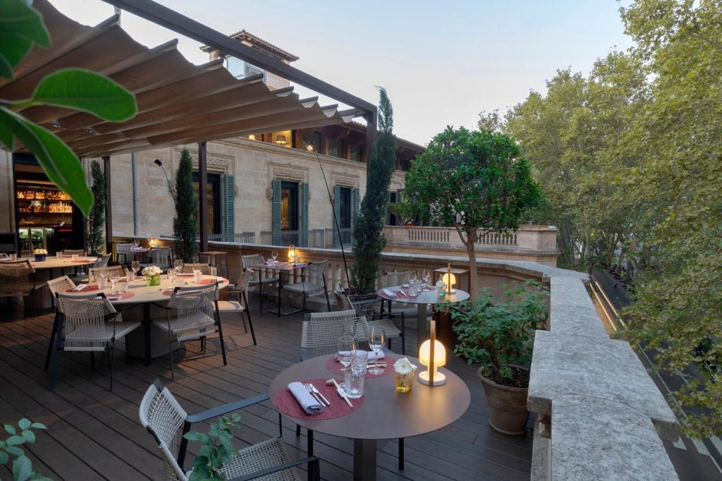 Elegant Spanish boutique hotel with stone facade, ornate balconies, and wrought-iron details in warm evening lighting on historic street