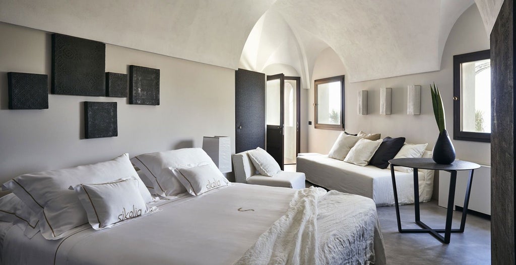 Elegant executive suite with panoramic Mediterranean view, minimalist white decor, plush king bed, and expansive windows overlooking Italian coastal landscape