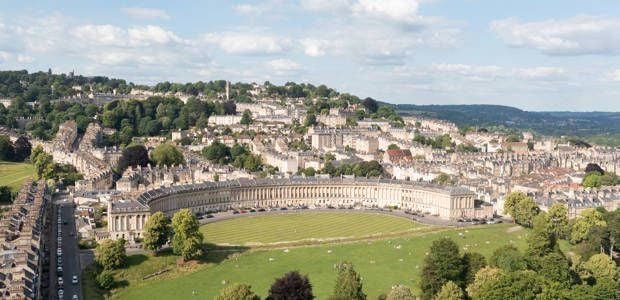 Elegant Georgian-style hotel with stone facade and majestic columns, set against lush green gardens in scenic Bath, United Kingdom.