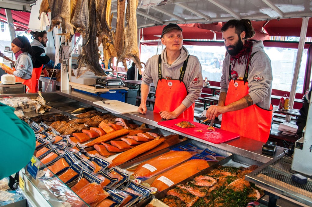 Elegant seafood platter with fresh Norwegian salmon, shrimp, and local delicacies against a rustic wooden backdrop in Bergen's historic harbor