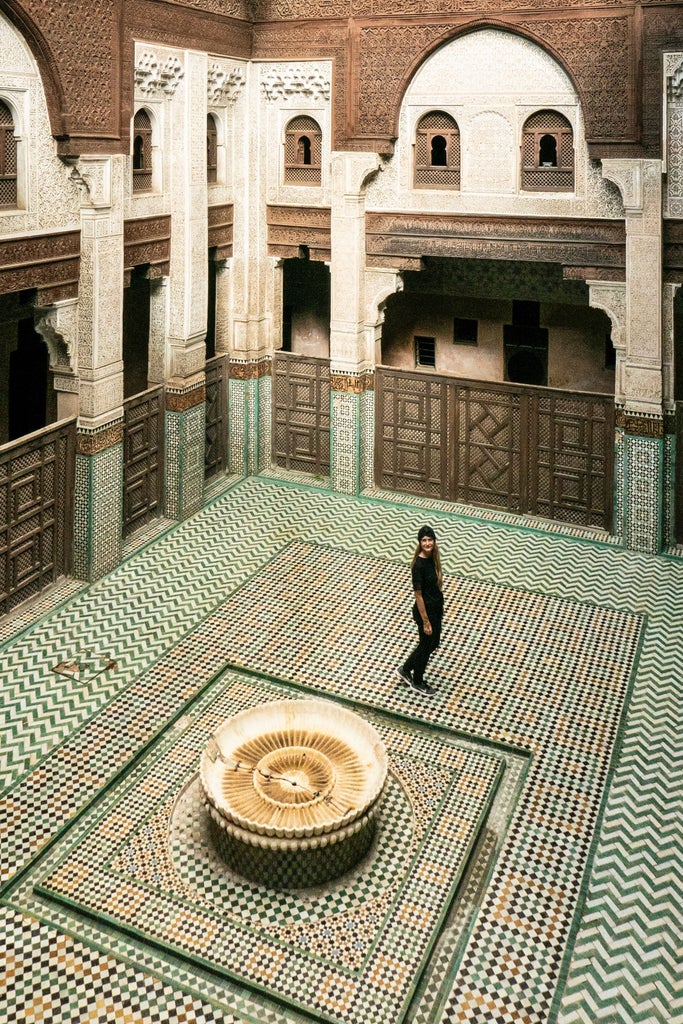 Ancient fortified gate of Bab Mansour in Meknes, Morocco, featuring intricate Islamic tilework, massive wooden doors, and ornate horse-shoe arches