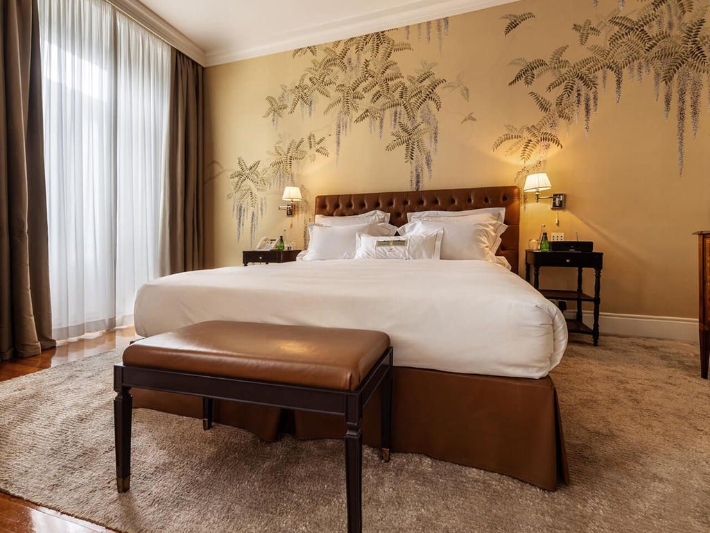 Opulent grand suite at Vidago Palace Hotel, featuring elegant cream-toned decor, plush king bed, antique furniture, and panoramic Portuguese landscape views