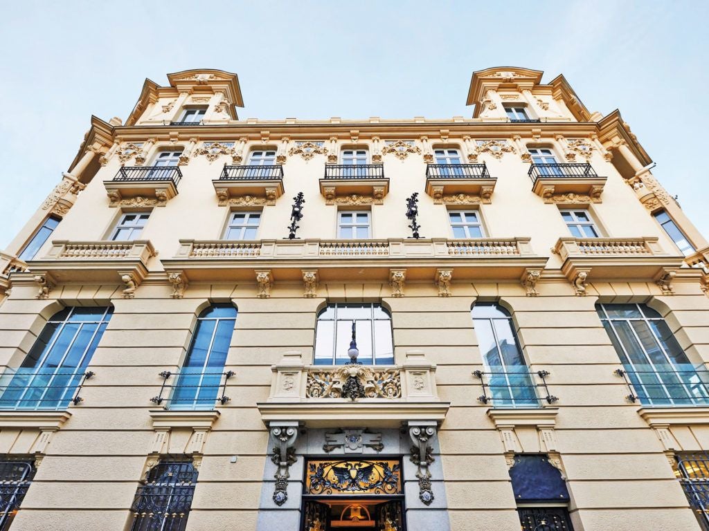 Elegant boutique hotel with white facade, classic Spanish architecture, luxurious spa entrance, and ornate balconies in central Madrid location