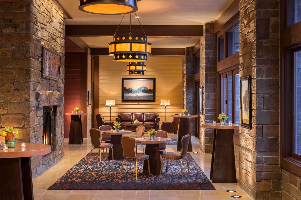 Snow-covered Four Seasons resort nestled in Wyoming mountains, featuring stone facade, expansive windows, and grand porte-cochère entrance