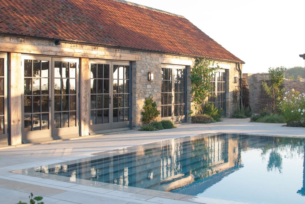 Elegant stone country house with manicured gardens, nestled in the UK countryside, showcasing refined architecture and lush green landscape at a luxury estate retreat.