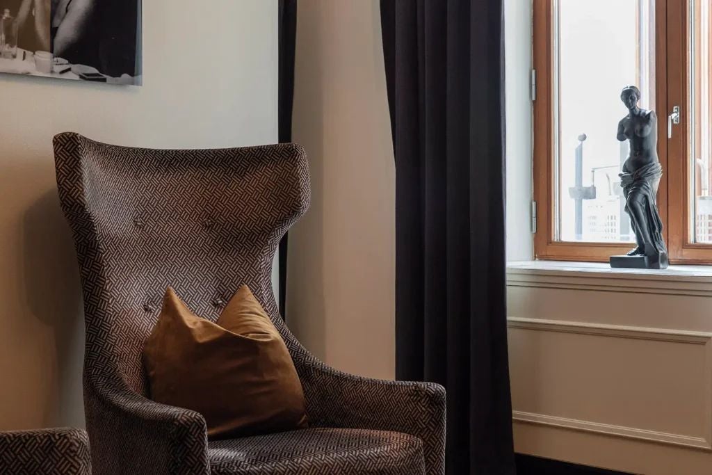 Elegant junior suite at Scenset Hotel with plush king bed, contemporary Swedish design, warm neutral tones, and floor-to-ceiling windows overlooking cityscape