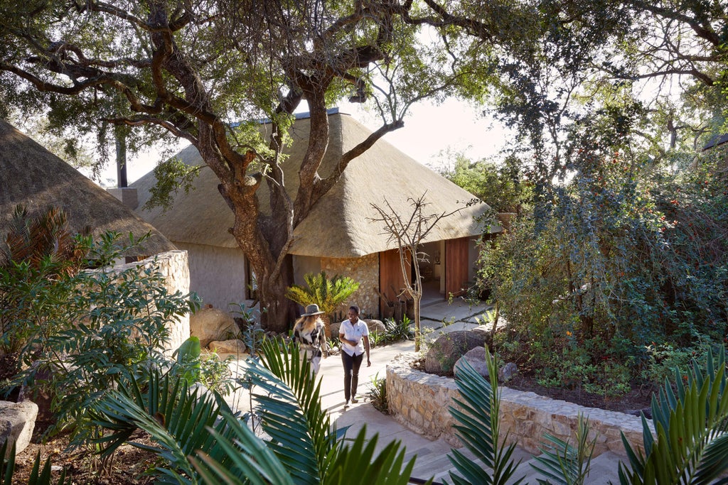 Luxurious safari lodge with private deck overlooking African bush, thatched roof, and elegant colonial-style furnishings at dusk