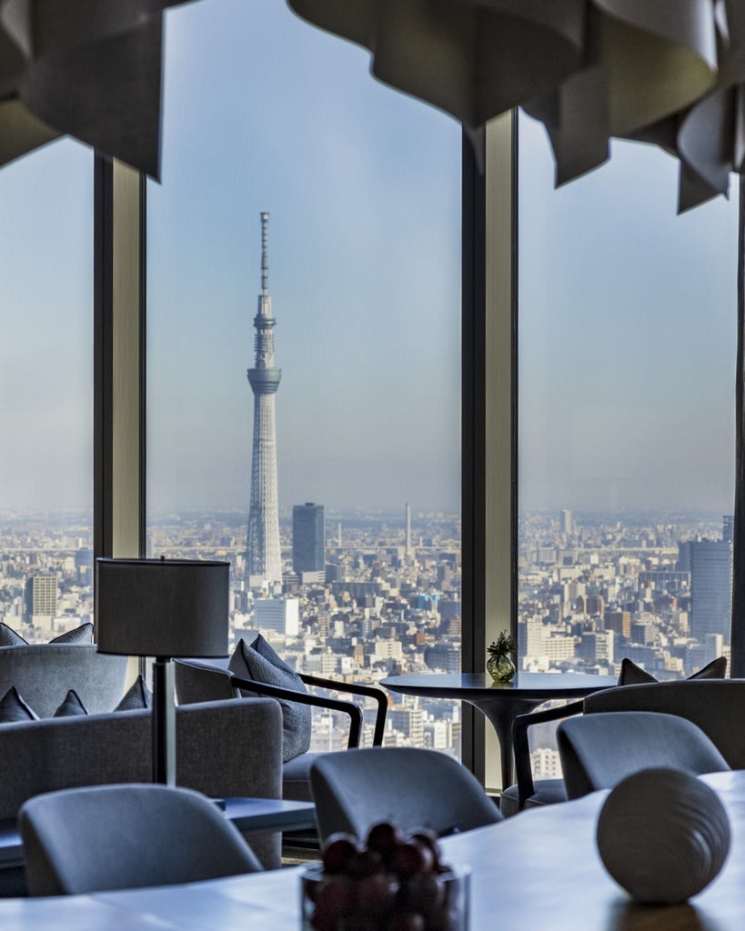 Modern luxury hotel room with floor-to-ceiling windows, minimalist decor, white bedding, wood accents, and panoramic Tokyo cityscape views