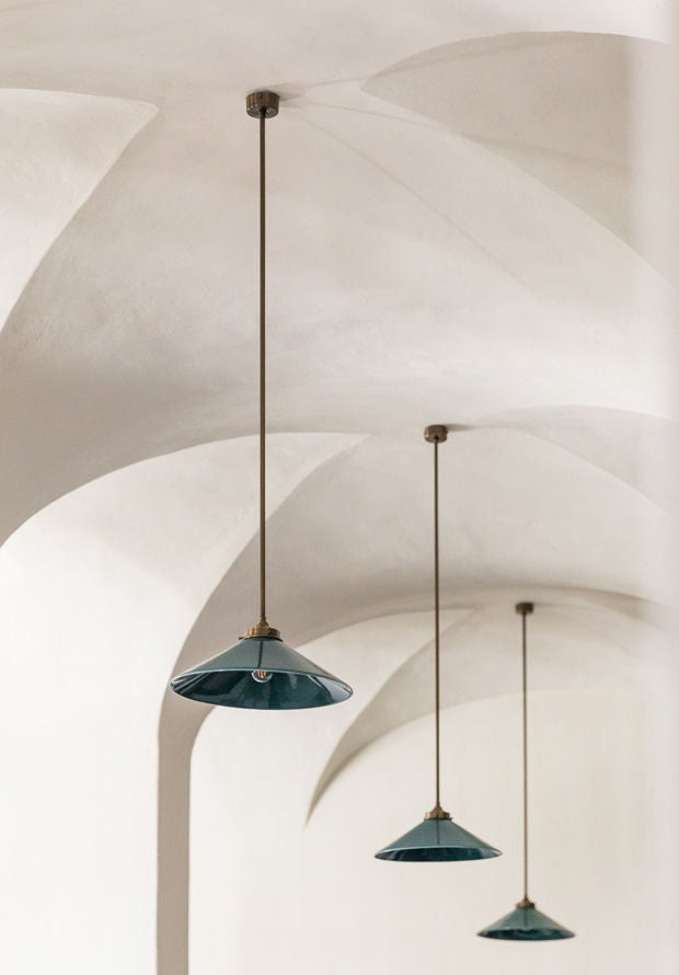 Elegant rustic-luxe stone villa with arched doorways nestled among olive trees at sunset in Portugal's rural Alentejo landscape