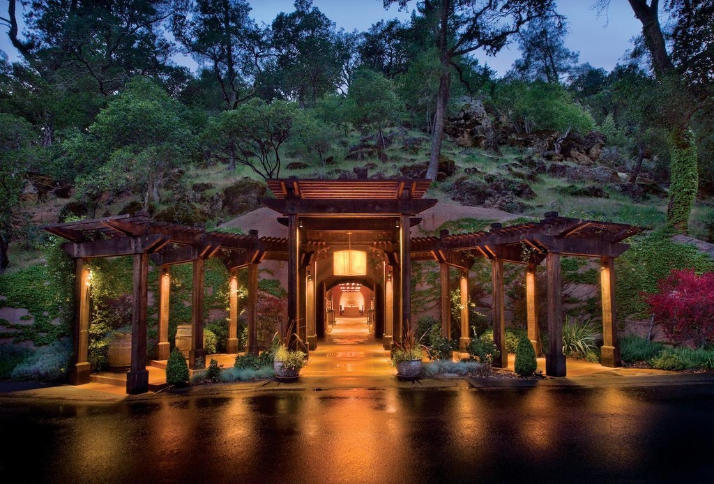Modern luxury lodge nestled among towering oak trees, featuring stone walls, wood beams, and a private deck overlooking Napa Valley