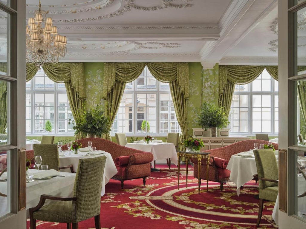 Elegant white Edwardian facade of The Goring London hotel with ornate columns, luxurious entrance awning, and manicured garden borders