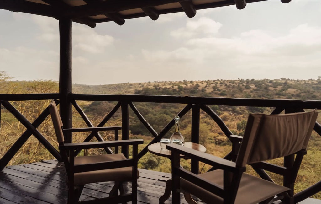 Luxury safari lodge nestled on hillside with floor-to-ceiling windows, stone walls and thatched roof overlooking Nairobi National Park