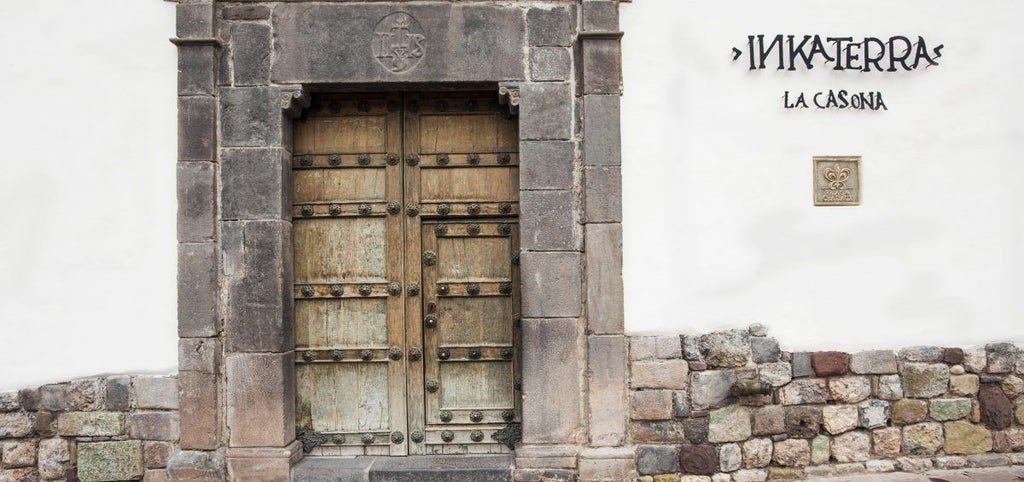 Historic stone colonial mansion with elegant courtyard garden, terra cotta roof tiles and wrought iron balconies in Cusco's historic district