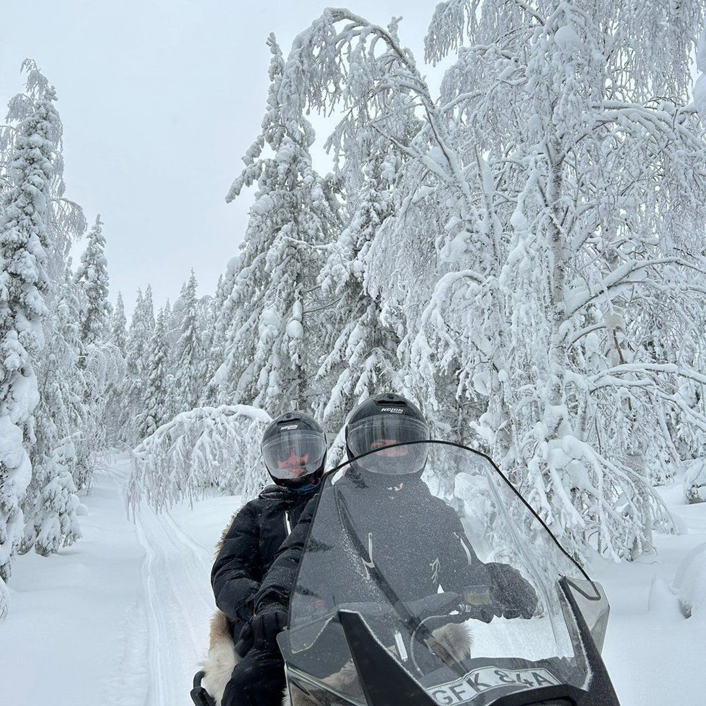 Floating luxury hotel with circular wooden structure on frozen river, surrounded by snow-covered pine trees in Arctic Swedish wilderness