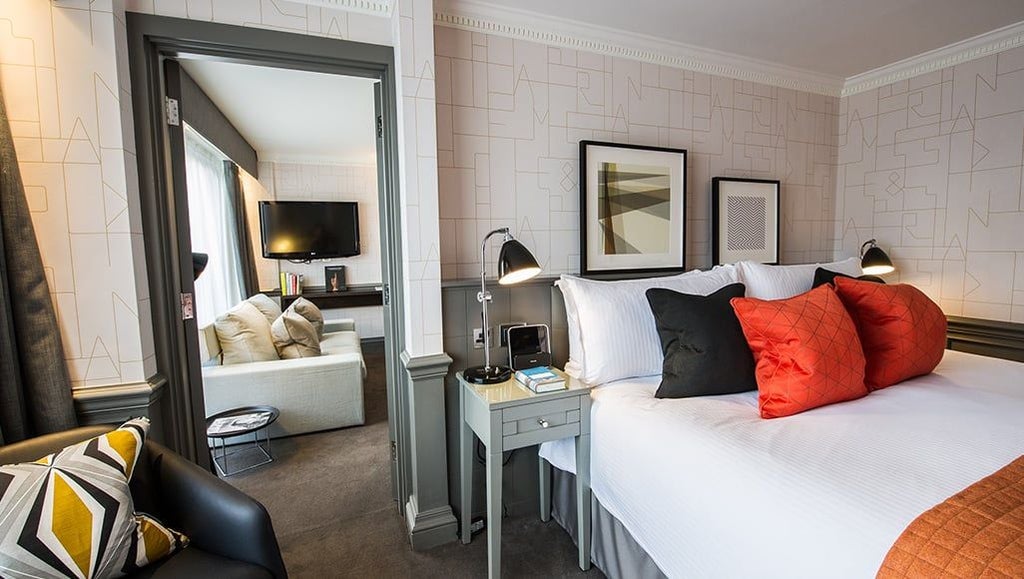 Elegant deluxe hotel room with plush white bedding, contemporary design, and soft neutral tones, showcasing modern luxury at the design-focused boutique accommodation.