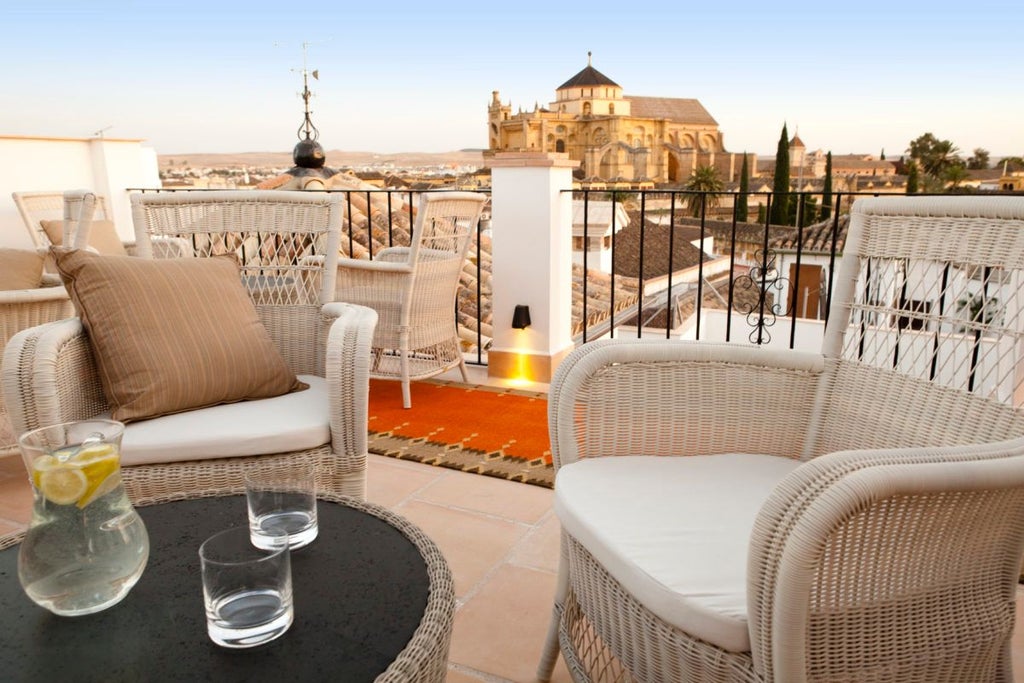 Elegant white-washed Spanish colonial hotel with ornate balconies overlooking historic Córdoba, featuring intricate Moorish architectural details and lush courtyard garden