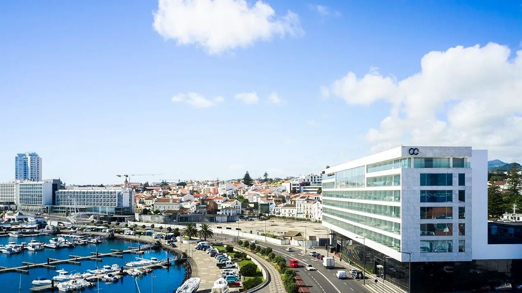 Modern luxury hotel with sleek white facade, glass balconies, and rooftop pool overlooking the Atlantic Ocean in Ponta Delgada, Azores