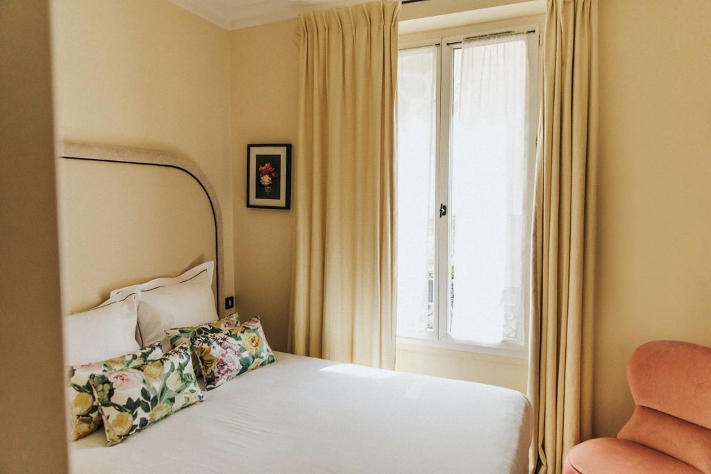 Elegant single room at Hôtel Bienvenue, featuring soft pastel walls, vintage-inspired furnishings, plush white bedding, and warm ambient lighting in Paris