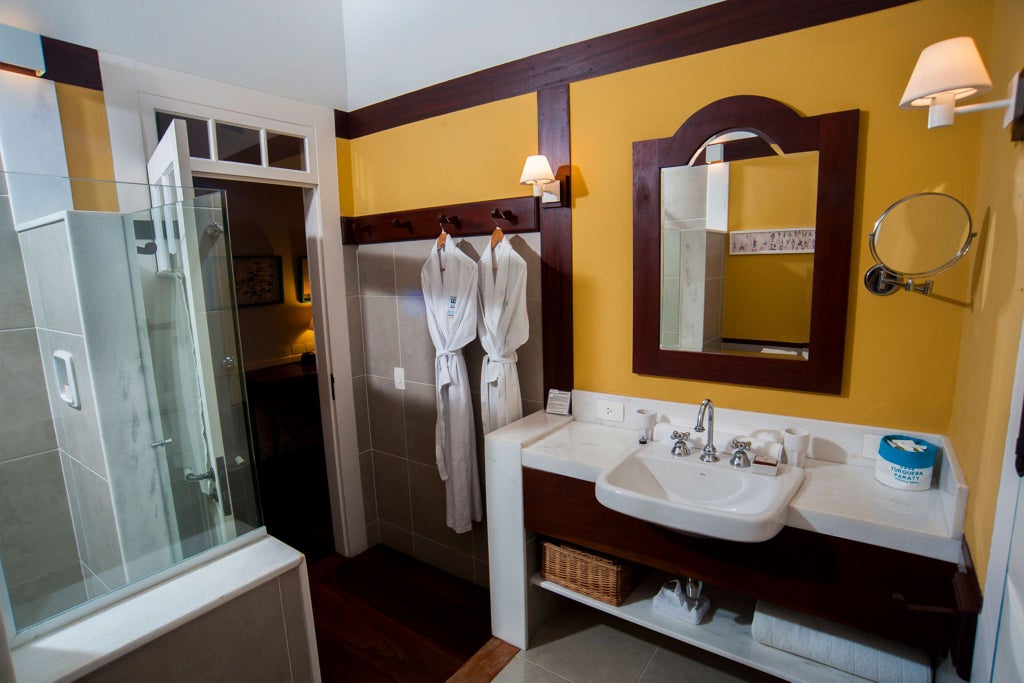 Elegant turquoise-themed luxury hotel suite with king-sized bed, minimalist decor, white walls, and Brazilian coastal design elements