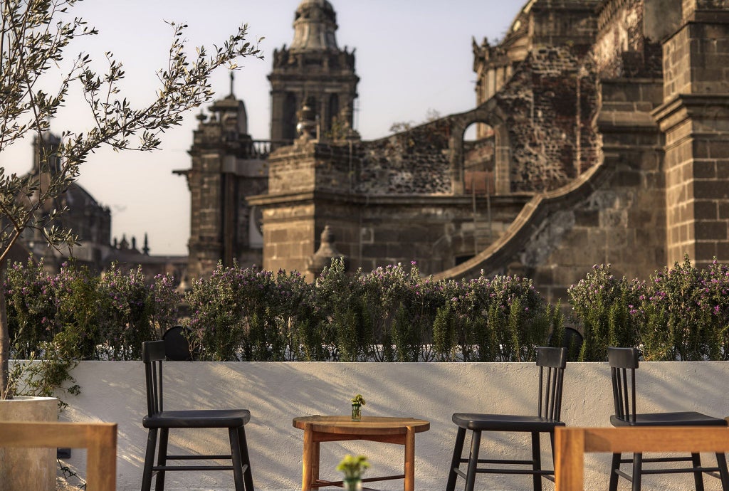 Elegant minimalist hotel courtyard with stone walls, greenery, modern furniture, and soft natural light in Mexico City's historic center