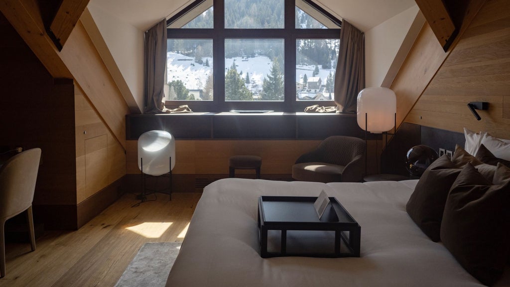 Luxurious Swiss alpine hotel suite with minimalist design, wooden floors, mountain view, modern fireplace, and elegant contemporary furnishings in neutral tones