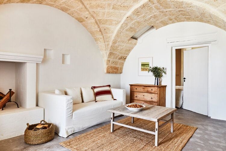 Elegant Mediterranean suite with rustic stone walls, plush white bedding, and panoramic view of lush olive grove at luxurious Italian countryside resort