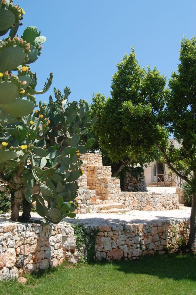 Rustic stone farmhouse at sunset, nestled in Puglia's rolling countryside with olive groves, warm terracotta tones and elegant Mediterranean architectural details