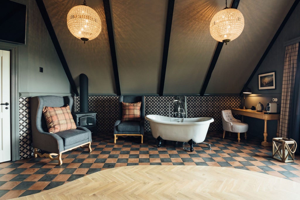 Elegant mini suite at Skálakot Manor Hotel with plush white bedding, rustic wooden furniture, and panoramic Icelandic landscape view through large windows