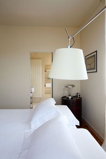 Elegant Italian villa bedroom with soft rosemary-toned walls, luxurious white linens, rustic wooden floors, and panoramic countryside view through large windows