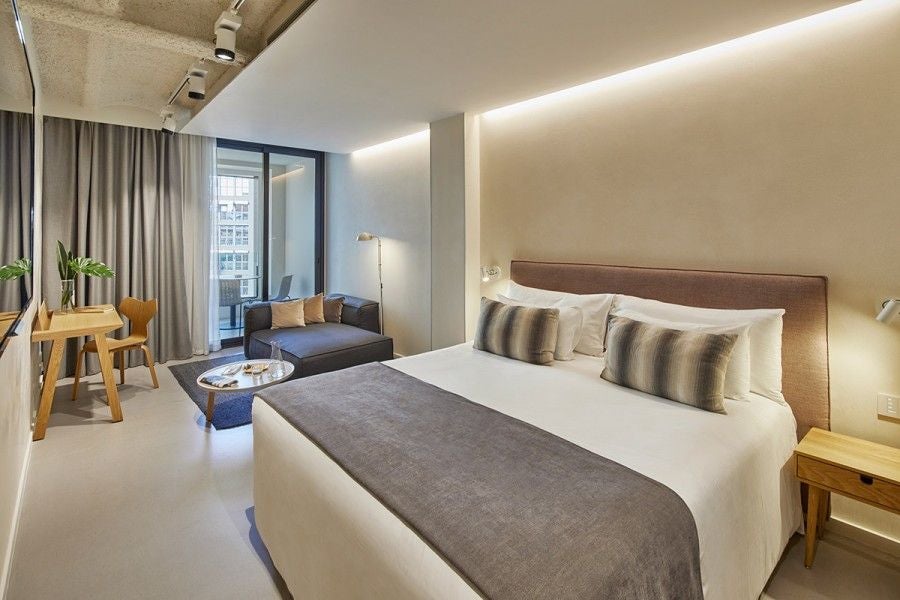 Modern minimalist hotel room with white walls, sleek gray headboard, crisp white bedding, and elegant minimalist decor in Barcelona's Ohla Eixample hotel