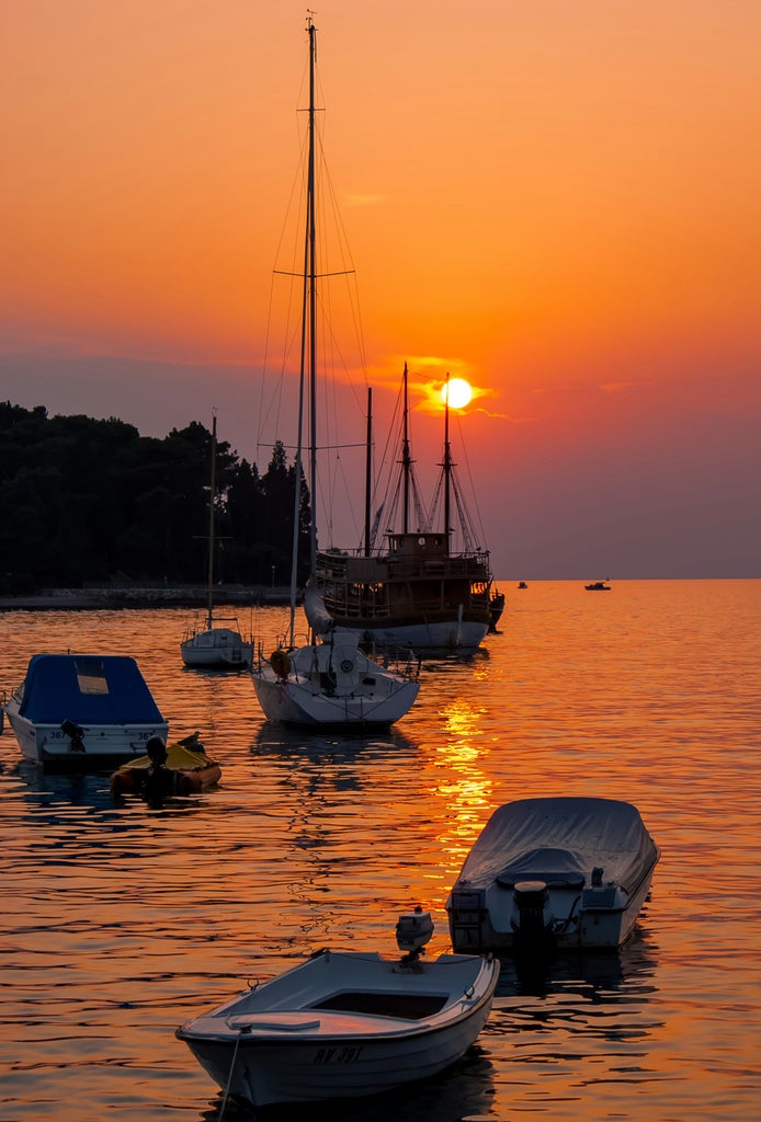 Elegant yacht cruising through crystal-clear turquoise waters near scenic Croatian islands, with ancient coastal towns in background