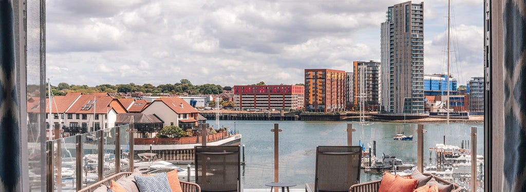 Luxurious marina view suite at Harbour Hotel Southampton, featuring modern decor, expansive balcony, and panoramic waterfront scenery through floor-to-ceiling windows