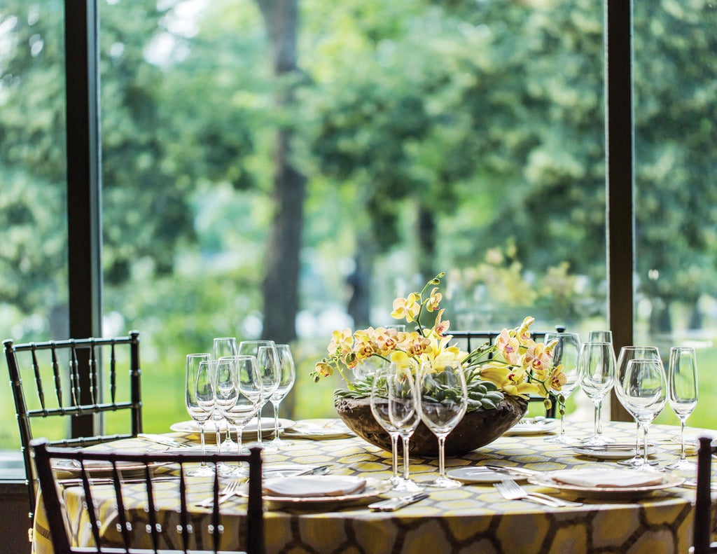 Elegant glass high-rise hotel overlooking Boston Public Garden, featuring classic limestone facade and illuminated entrance with valet service