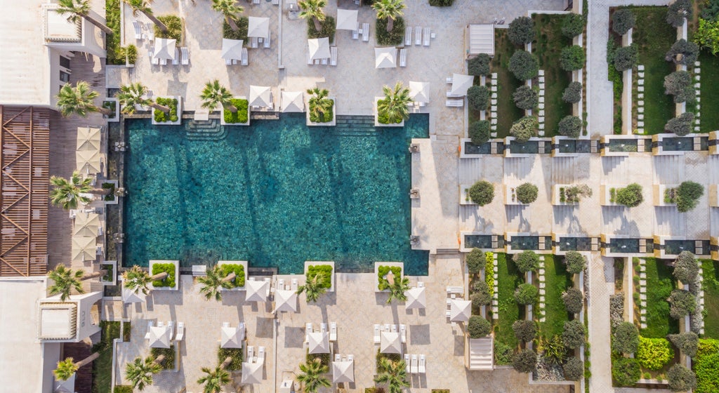 Luxury beachfront resort features elegant white Mediterranean architecture, palm-lined pools, and panoramic views of the Gulf of Tunis