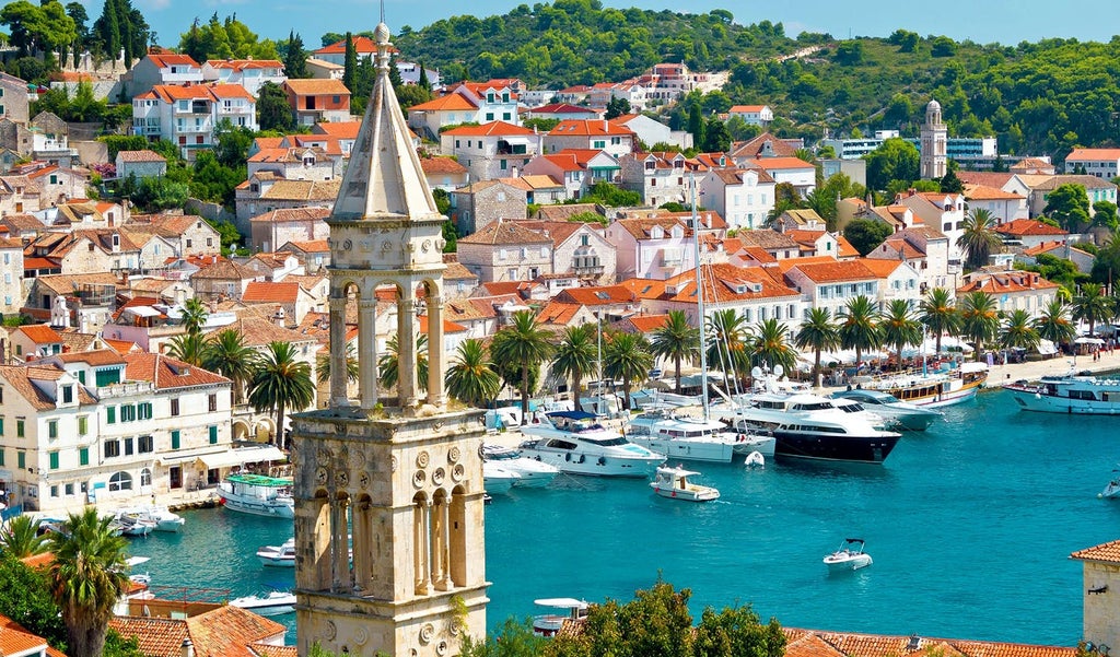 Scenic aerial view of Dubrovnik's historic Old Town with terracotta rooftops, limestone walls and turquoise Adriatic Sea backdrop