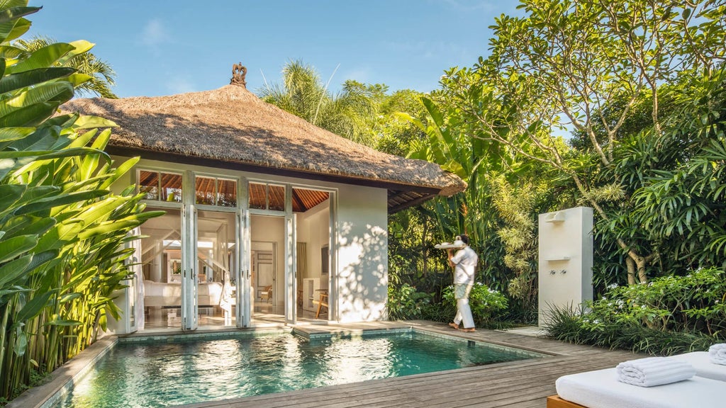 Luxurious Balinese villa with private infinity pool surrounded by lush tropical garden, featuring natural stone walls and teak details