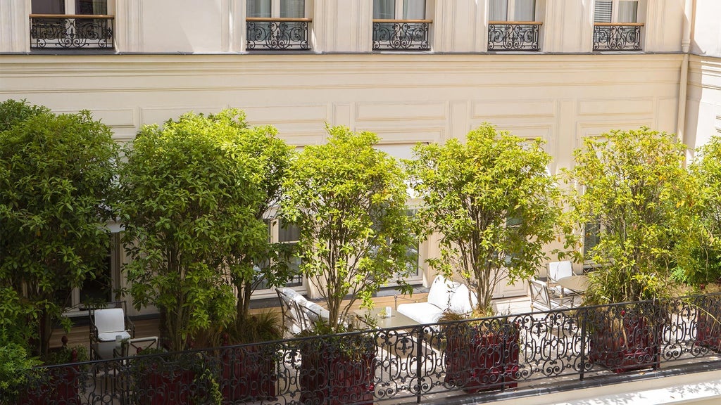 Elegant Parisian luxury hotel exterior with neoclassical architecture, grand windows, and manicured landscaping along a prestigious street near the Eiffel Tower