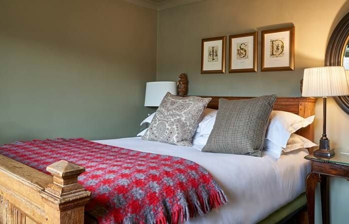 Elegant single room at historic Lygon Arms hotel, featuring warm wooden furnishings, soft neutral tones, and inviting traditional British countryside decor