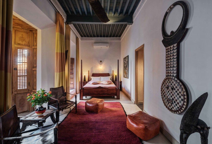 Luxurious Moroccan riad featuring a central courtyard with ornate tilework, elegant archways, and a traditional fountain under palm trees